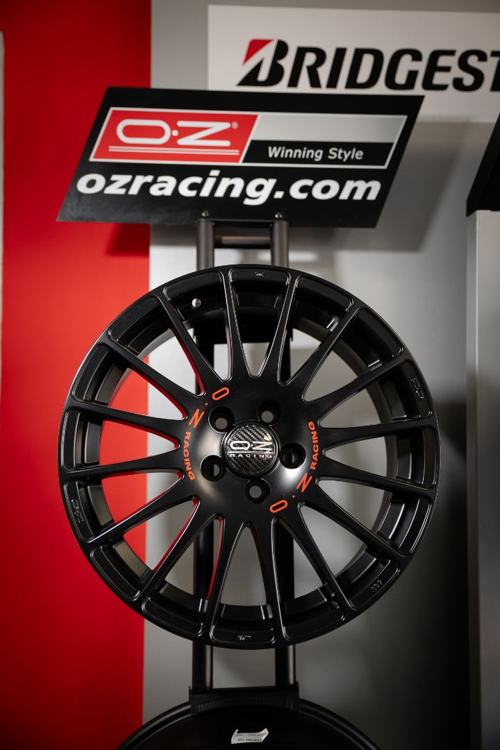 Cerchio OZ Racing nero opaco con scritte arancioni su espositore showroom Ermes Gomme Poirino