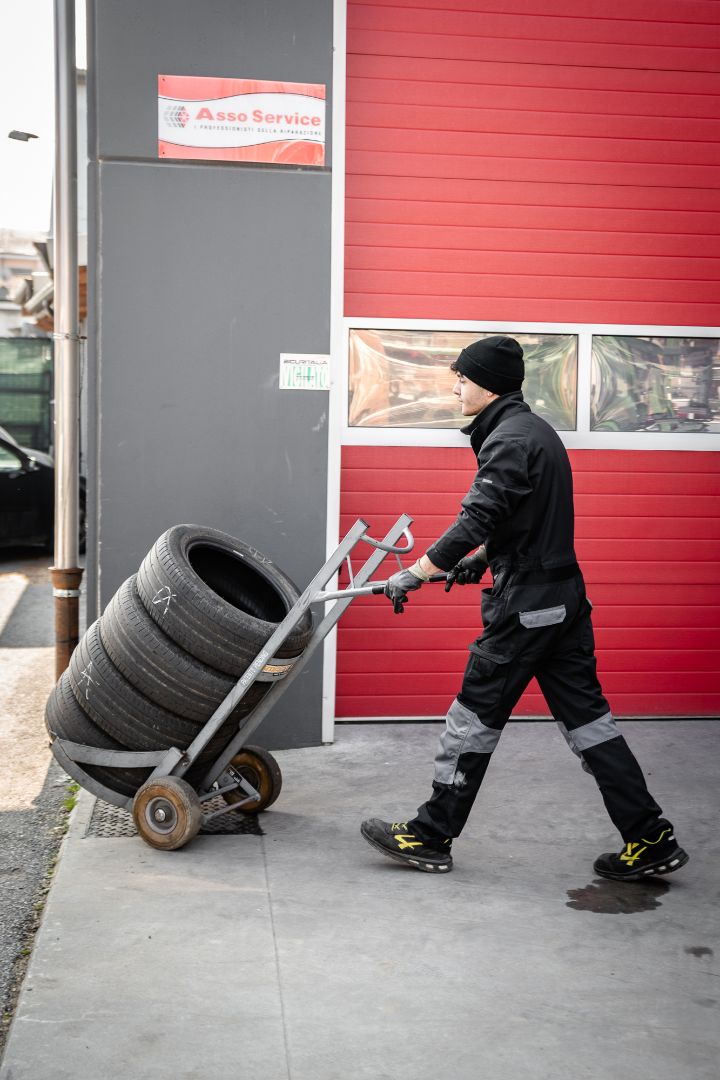 Tecnico trasporta pneumatici fuori dall'officina